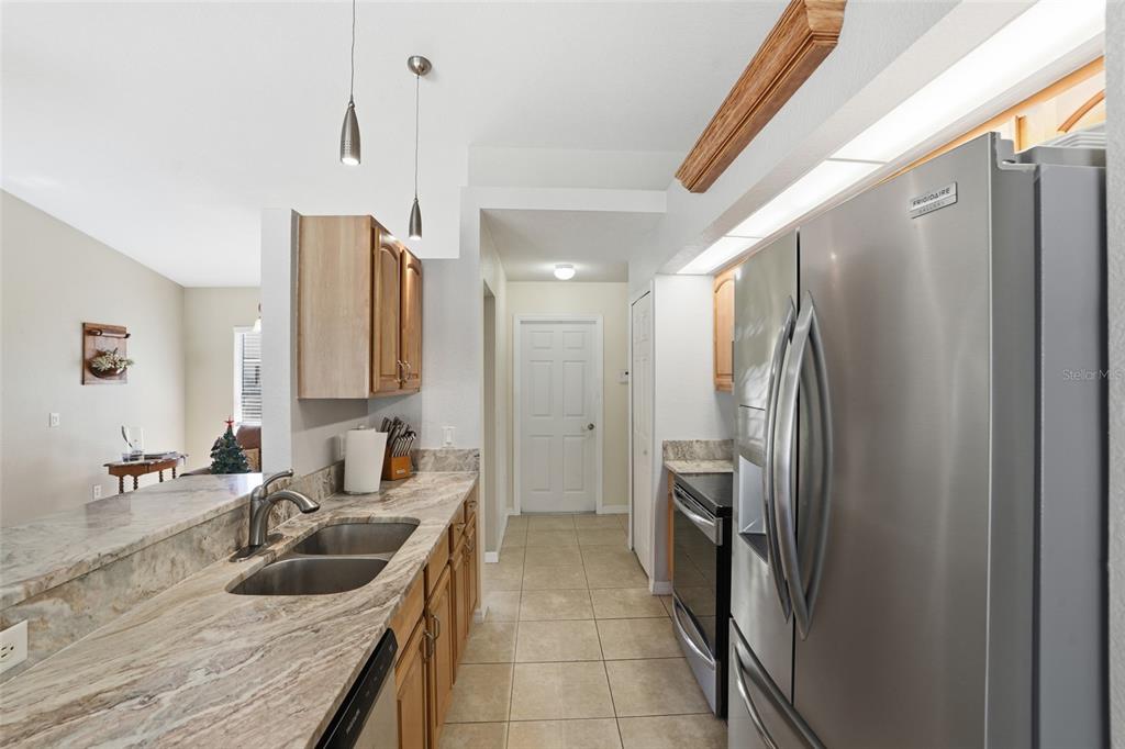A kitchen features wood cabinets, granite countertops, stainless steel appliances, and tile flooring — 2291 MEETZE STREET, PORT CHARLOTTE, FL