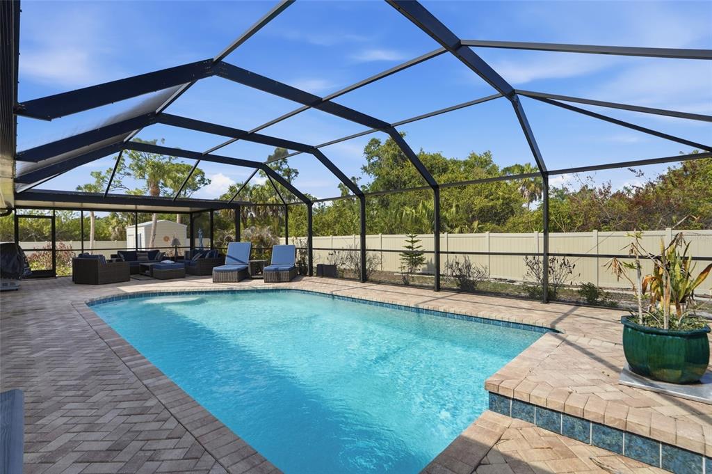 A swimming pool with a brick deck is enclosed by a screened lanai structure — 2291 MEETZE STREET, PORT CHARLOTTE, FL