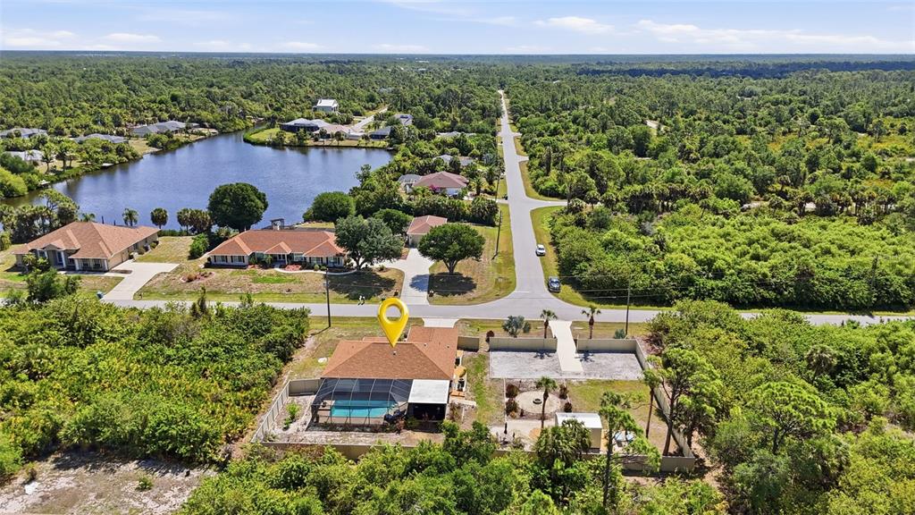 An aerial view shows a house with a pool and a large yard near water — 2291 MEETZE STREET, PORT CHARLOTTE, FL