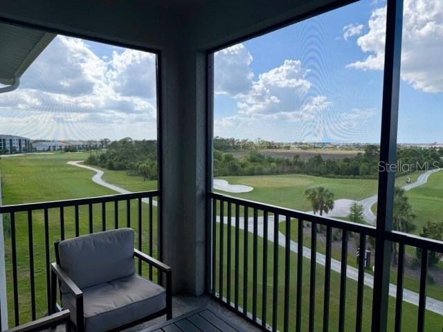A screened-in balcony overlooks a golf course with a paved path and green fairways — 12140 WELLEN GOLF STREET UNIT 402, VENICE, FL