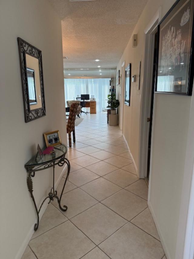 A tiled hallway leads from an entryway into a bright living area with large windows — 13678 Vía Flora # B, Delray Beach FL 33484, DELRAY BEACH, FL