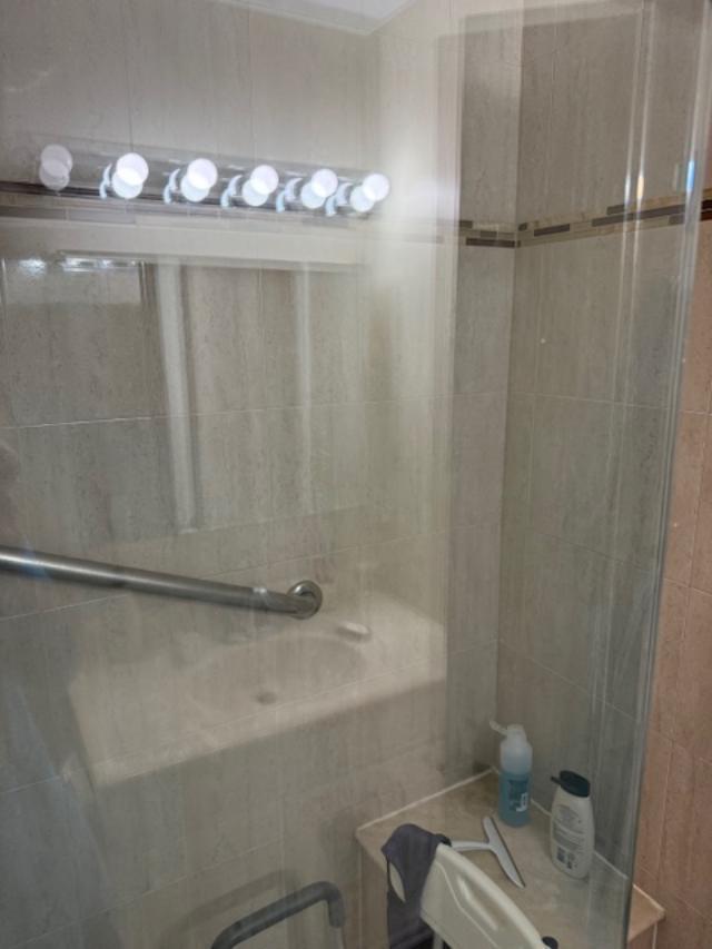 A tiled walk-in shower features a glass door, a grab bar, and a built-in seat — 13678 Vía Flora # B, Delray Beach FL 33484, DELRAY BEACH, FL