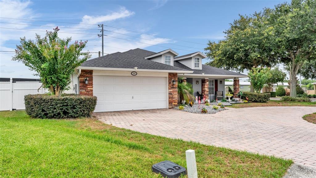 A single-story house features a white garage door, stone accents, and a paved driveway — 104 BENTLEY OAKS BOULEVARD, AUBURNDALE, FL