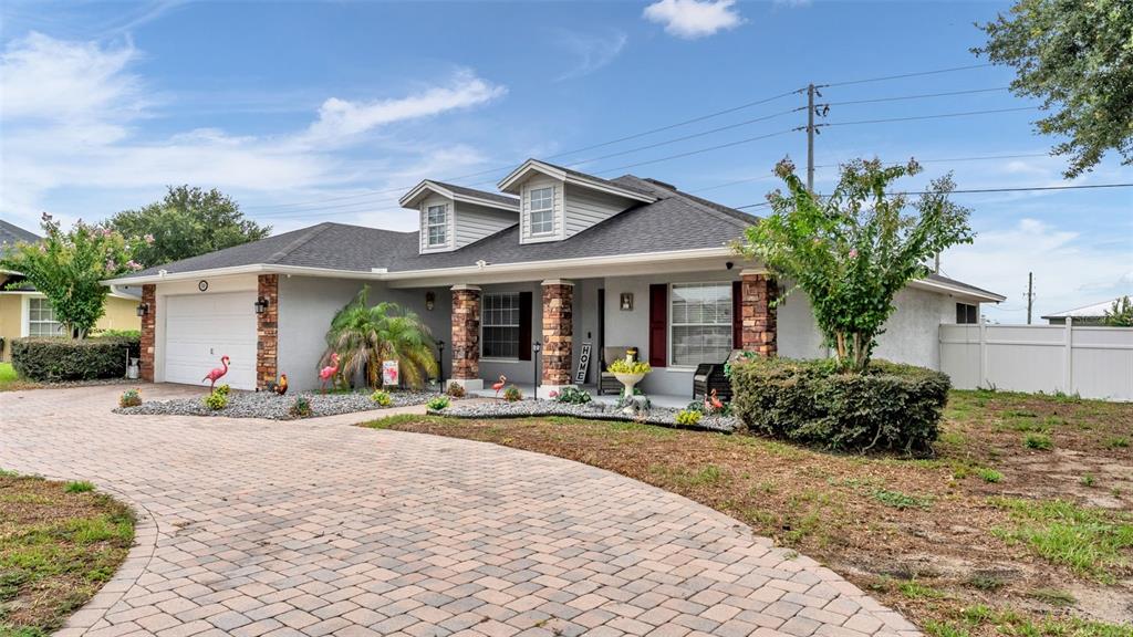 A single-story house with a stone-accented porch, gray siding, and a paved driveway — 104 BENTLEY OAKS BOULEVARD, AUBURNDALE, FL