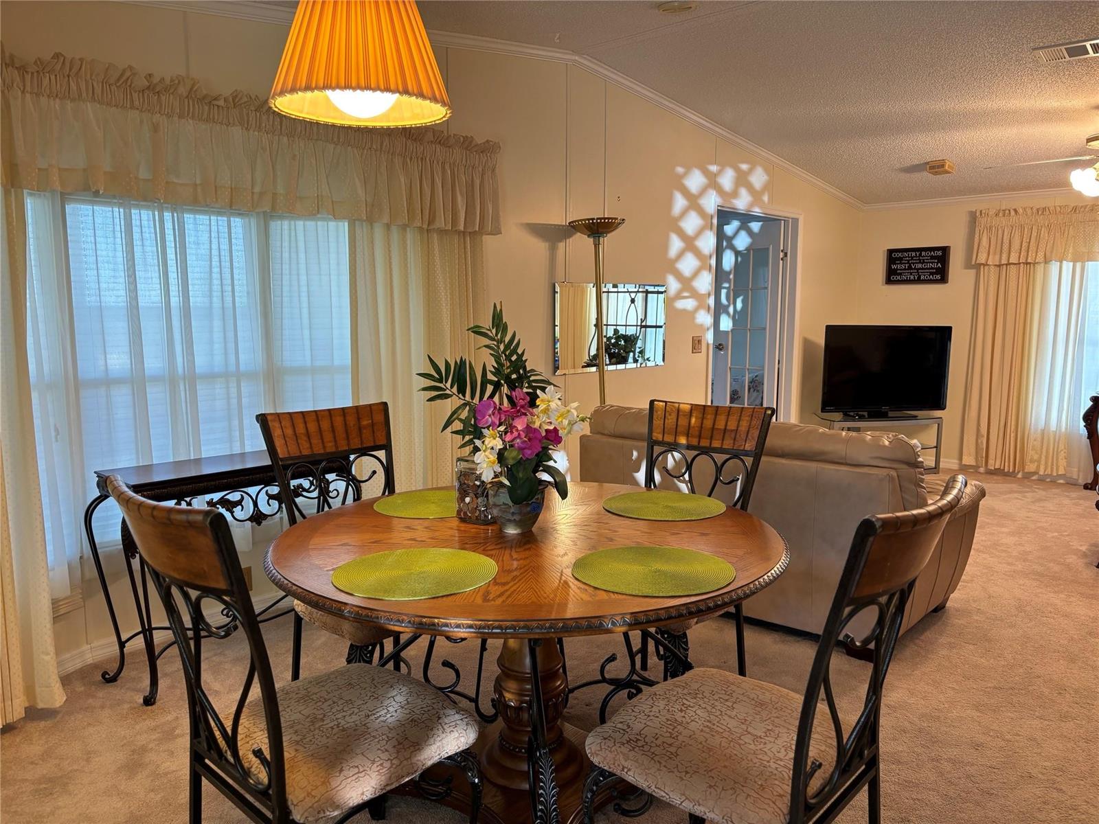 A dining area with a round wooden table, four chairs, and a living room beyond — 1759 SW 35th Circle, Okeechobee FL 34974, OKEECHOBEE, FL