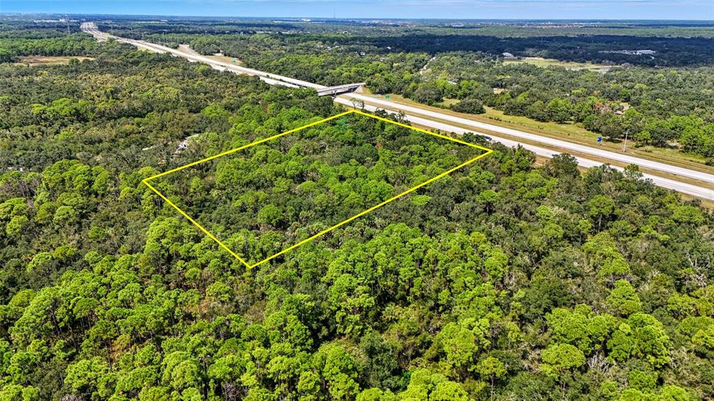 An aerial view shows a rectangular plot of land outlined in yellow near a highway — 0 S MOON DRIVE, VENICE, FL