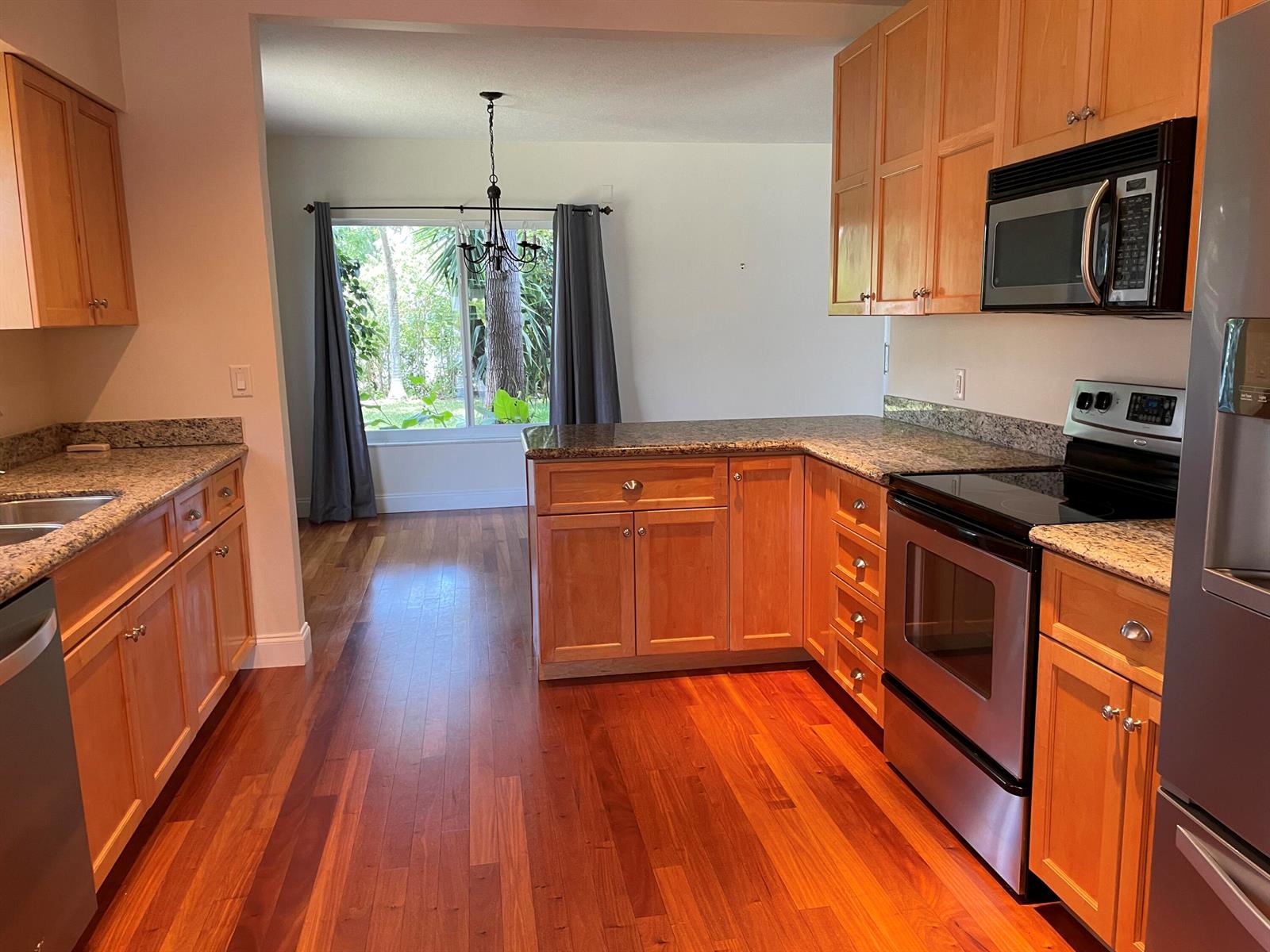 A kitchen with wood cabinets, granite countertops, and stainless steel appliances overlooks a dining area — 465 NE 34th Street, Boca Raton FL 33431, BOCA RATON, FL