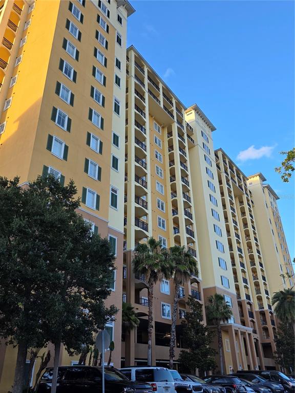 A tall, yellow multi-story apartment building features numerous balconies and green-shuttered windows — 8101 RESORT VILLAGE DRIVE UNIT 3904, ORLANDO, FL