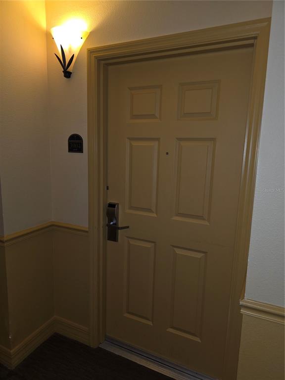A tan interior door with a keyless entry lock and a wall-mounted light fixture — 8101 RESORT VILLAGE DRIVE UNIT 3904, ORLANDO, FL