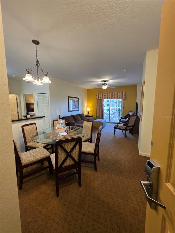 A dining area with a glass table and chairs opens into a carpeted living room — 8101 RESORT VILLAGE DRIVE UNIT 3904, ORLANDO, FL