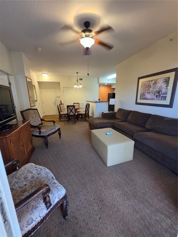 A living room with a brown sectional sofa, patterned armchairs, and a dining area beyond — 8101 RESORT VILLAGE DRIVE UNIT 3904, ORLANDO, FL