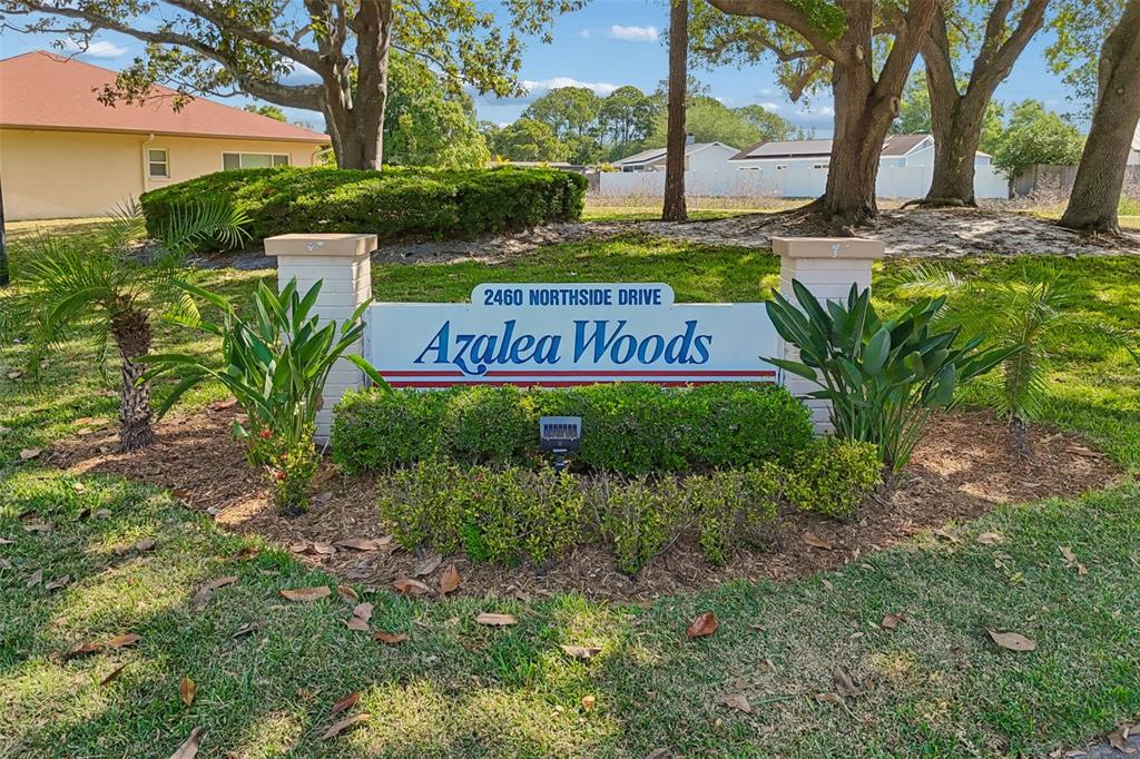 A stone monument sign for Azalea Woods sits in a landscaped lawn with trees — 2460 NORTHSIDE DRIVE UNIT 604, CLEARWATER, FL