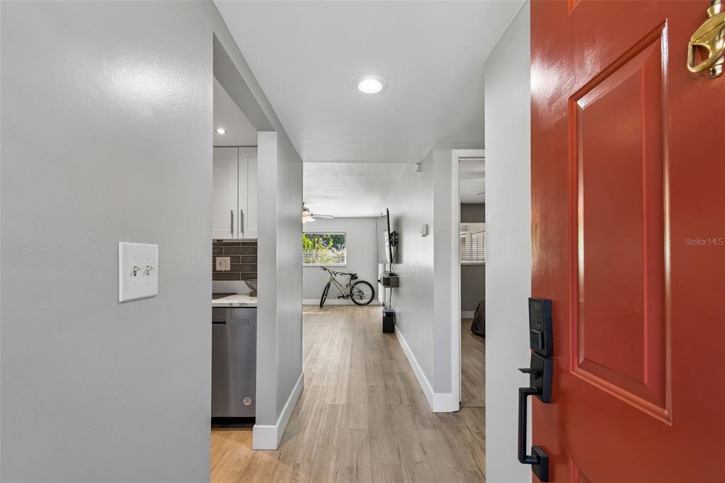 An entryway leads into a living area with light wood flooring and a kitchen visible — 2460 NORTHSIDE DRIVE UNIT 604, CLEARWATER, FL