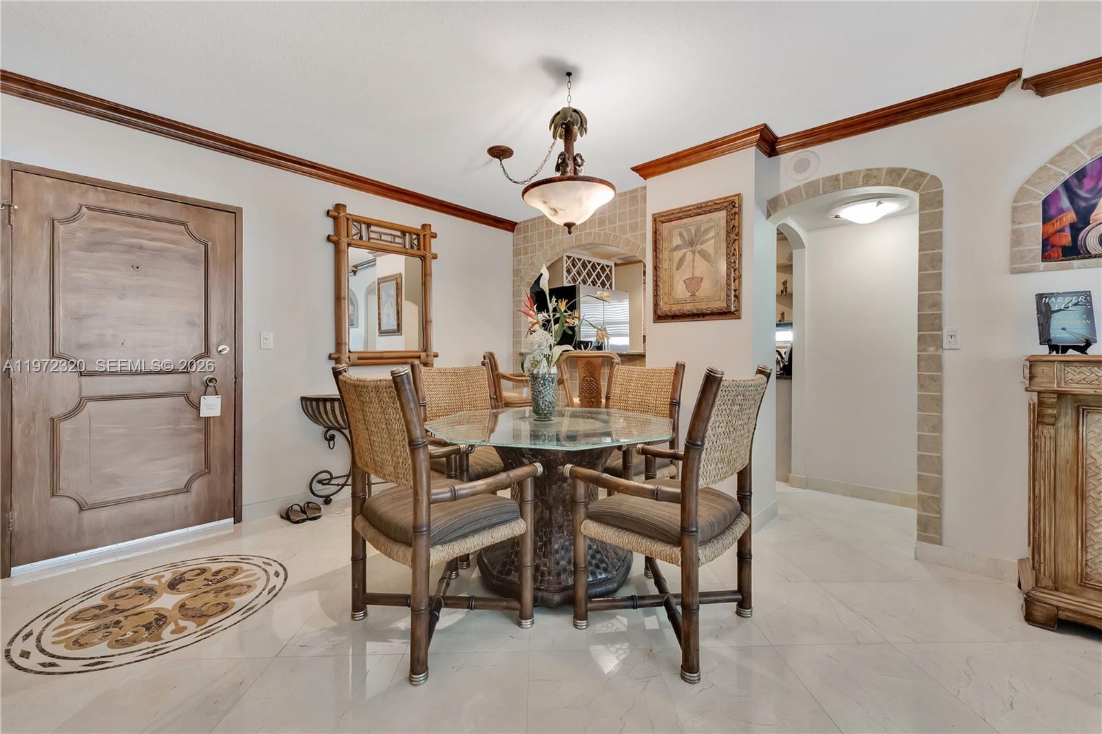 A dining area features a glass-topped table, bamboo-style chairs, and arched stone-tiled wall accents — 5555 Collins Ave # 5B, Miami Beach FL 33140, MIAMI BEACH, FL