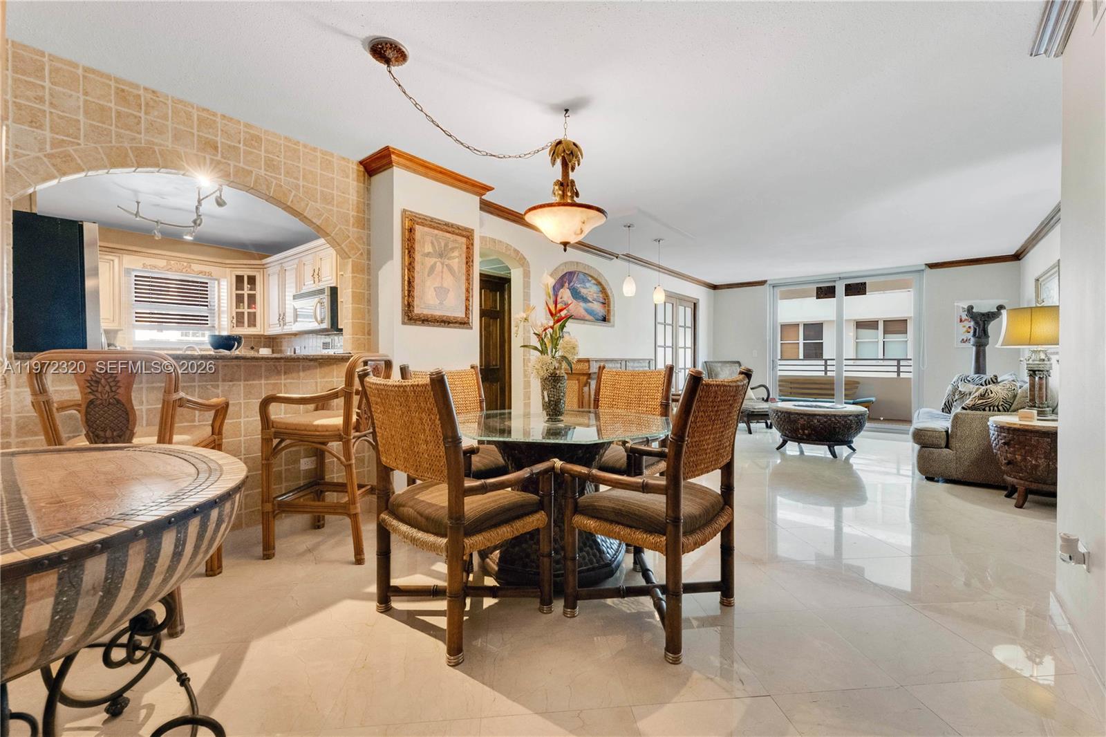 A dining area and living room feature tile floors, wicker furniture, and a kitchen pass-through — 5555 Collins Ave # 5B, Miami Beach FL 33140, MIAMI BEACH, FL