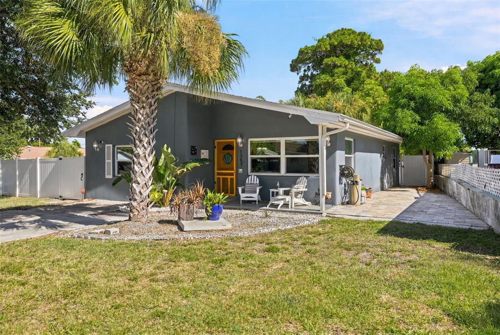 A gray single-story house features a yellow front door, palm tree, and paved patio area — 1257 FRANKLIN STREET, CLEARWATER, FL