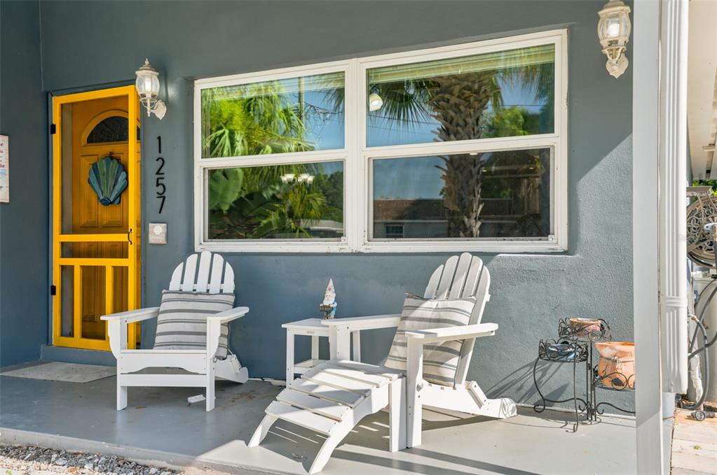 A gray exterior wall features a yellow screen door, two white chairs, and a window — 1257 FRANKLIN STREET, CLEARWATER, FL