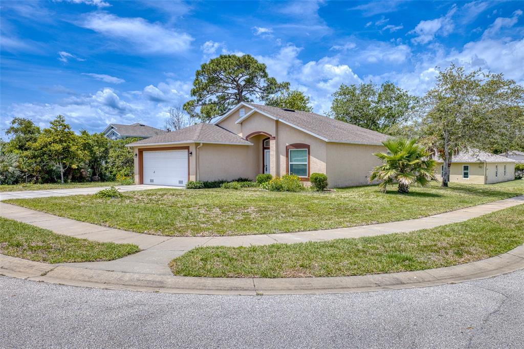 A single-story tan house with a two-car garage sits on a corner lot — 320 BROKEN OAK DRIVE, EDGEWATER, FL., FL