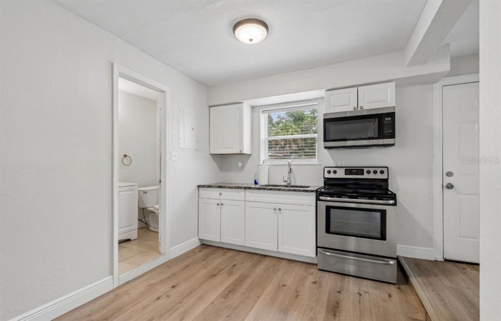 A kitchen with white cabinets, stainless steel appliances, and wood-look flooring — 725 21ST AVENUE S, ST PETERSBURG, FL