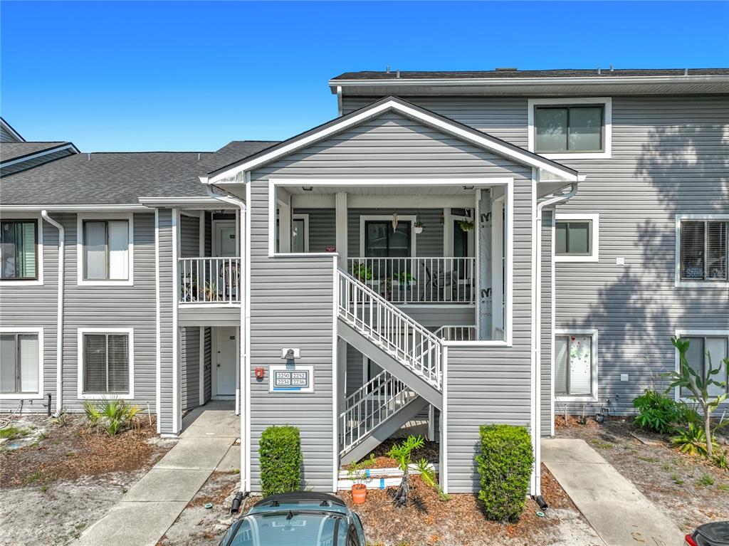 An exterior view of a two-story apartment building with gray siding and an outdoor staircase — 2234 STONINGTON AVENUE UNIT 2234, ORLANDO, FL