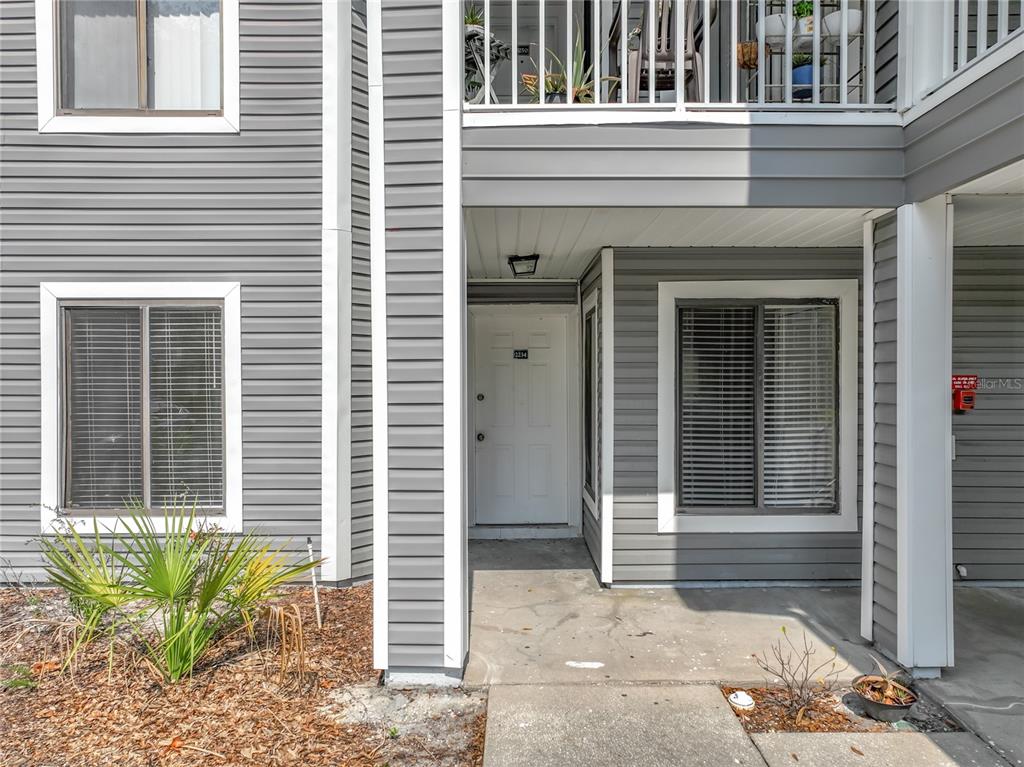 The exterior of a gray-sided apartment building features a ground-level entrance and a balcony above — 2234 STONINGTON AVENUE UNIT 2234, ORLANDO, FL