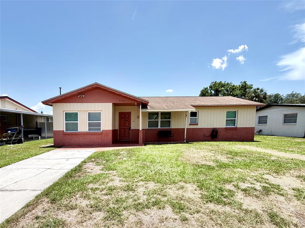 A single-story house with a red brick base, tan siding, and a brown shingled roof — 3306 W BURKE STREET, TAMPA, FL