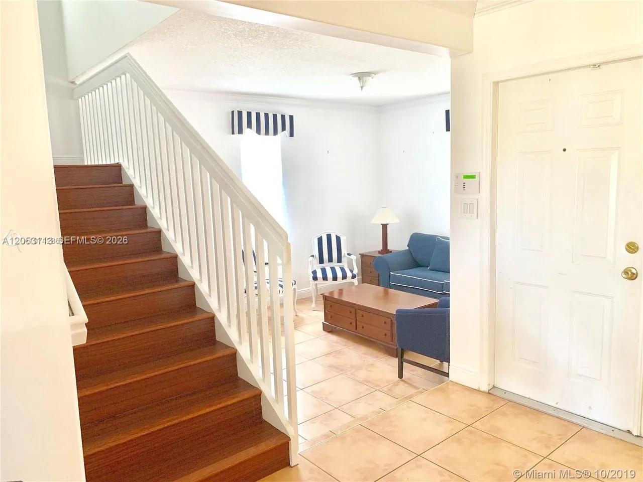 A staircase with wooden treads leads to an upper level beside a tiled living area — 16141 SW 96th Ter, Miami FL 33196, MIAMI, FL