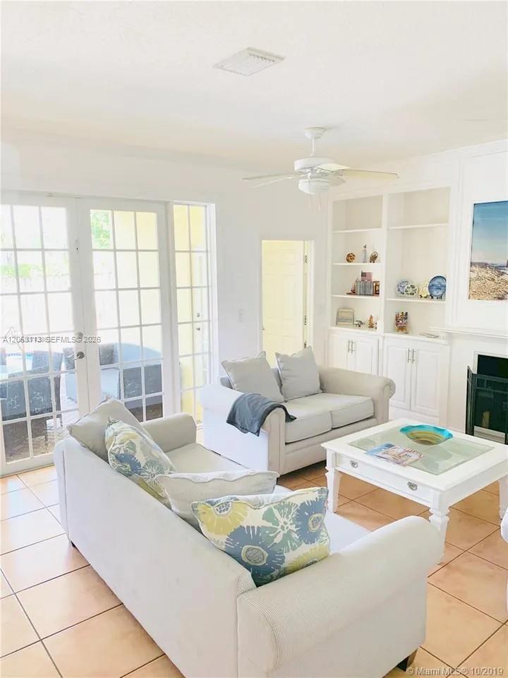 A living room features light-colored sofas, a white coffee table, built-in shelving, and glass doors — 16141 SW 96th Ter, Miami FL 33196, MIAMI, FL