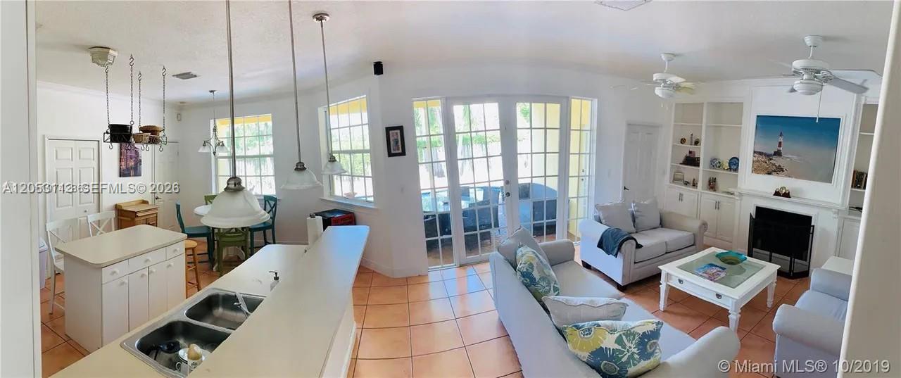 An open-concept living room and kitchen feature tile floors, white cabinetry, and glass patio doors — 16141 SW 96th Ter, Miami FL 33196, MIAMI, FL