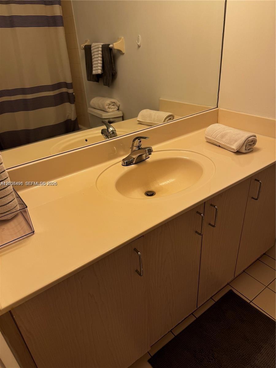 A bathroom features a beige vanity with a single sink, a large mirror, and a shower — 185 SE 14th Ter # 1812, Miami FL 33131, MIAMI, FL