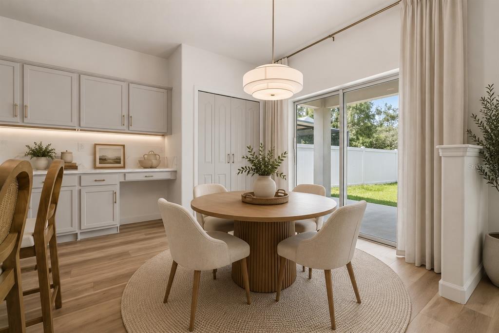 A dining room with a round wooden table, four chairs, and a built-in desk area — 12410 LATCHFORD STREAM PLACE, RIVERVIEW, FL