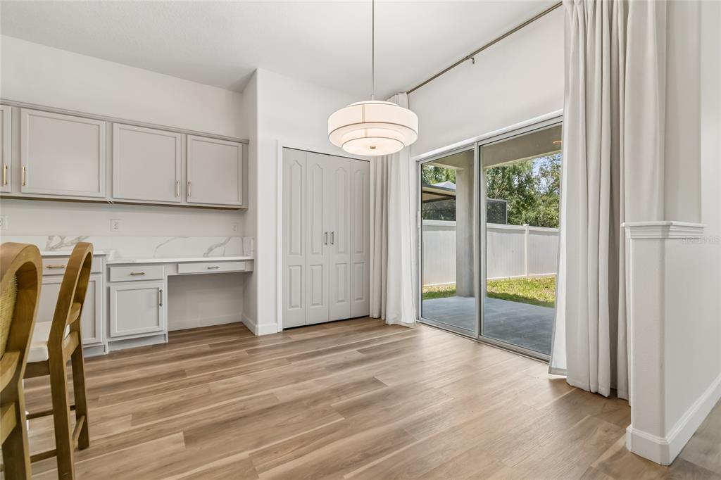 A dining area with light wood floors, built-in cabinetry, a pendant light, and sliding glass doors — 12410 LATCHFORD STREAM PLACE, RIVERVIEW, FL