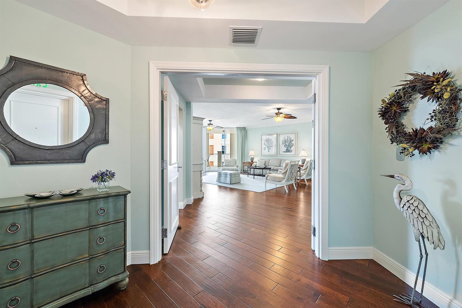 A foyer with a dresser and mirror leads into a living room with hardwood floors — 700 S Us Highway 1 # 406, Jupiter FL 33477, JUPITER, FL