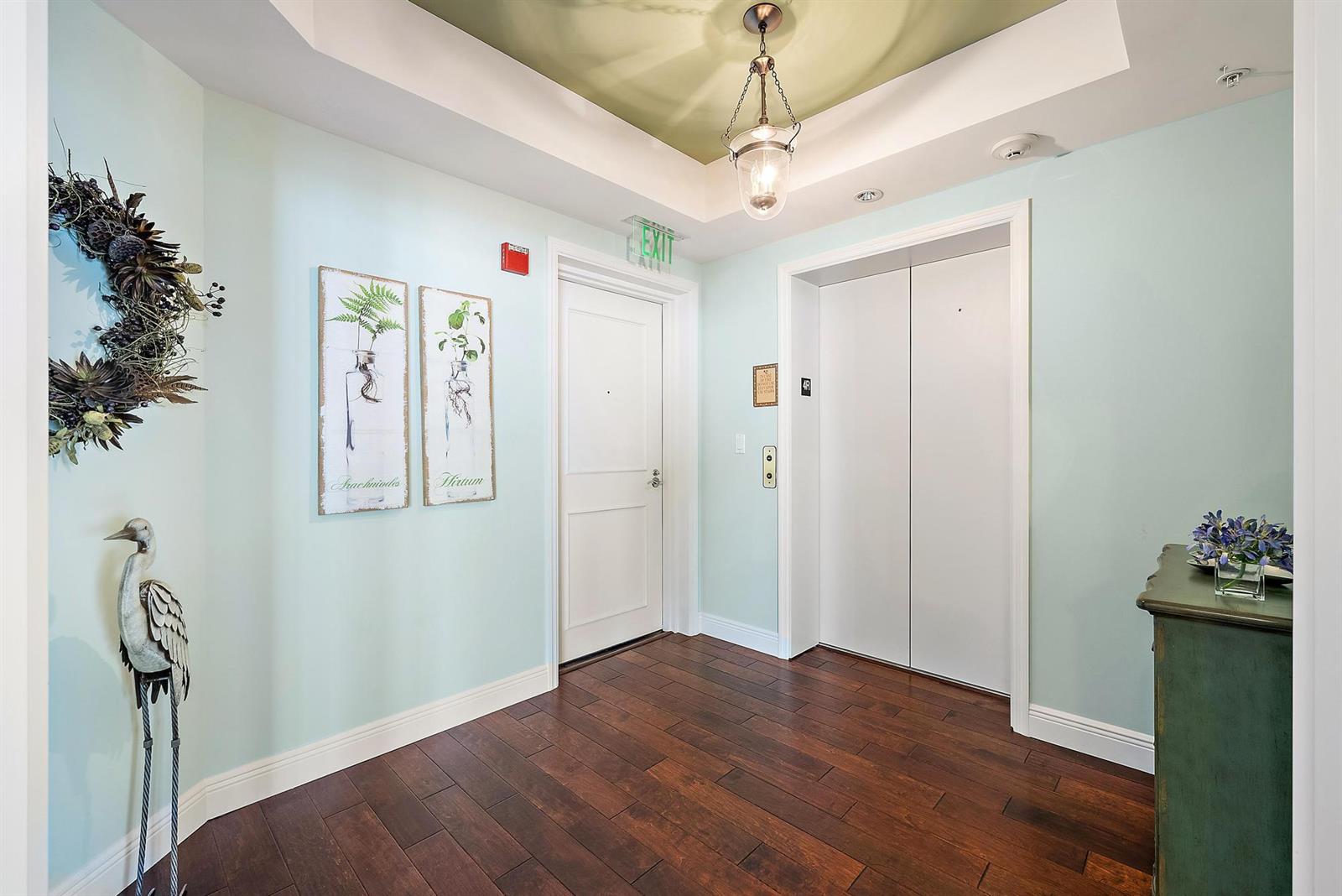 A foyer features light blue walls, dark wood flooring, an elevator, and a white door — 700 S Us Highway 1 # 406, Jupiter FL 33477, JUPITER, FL