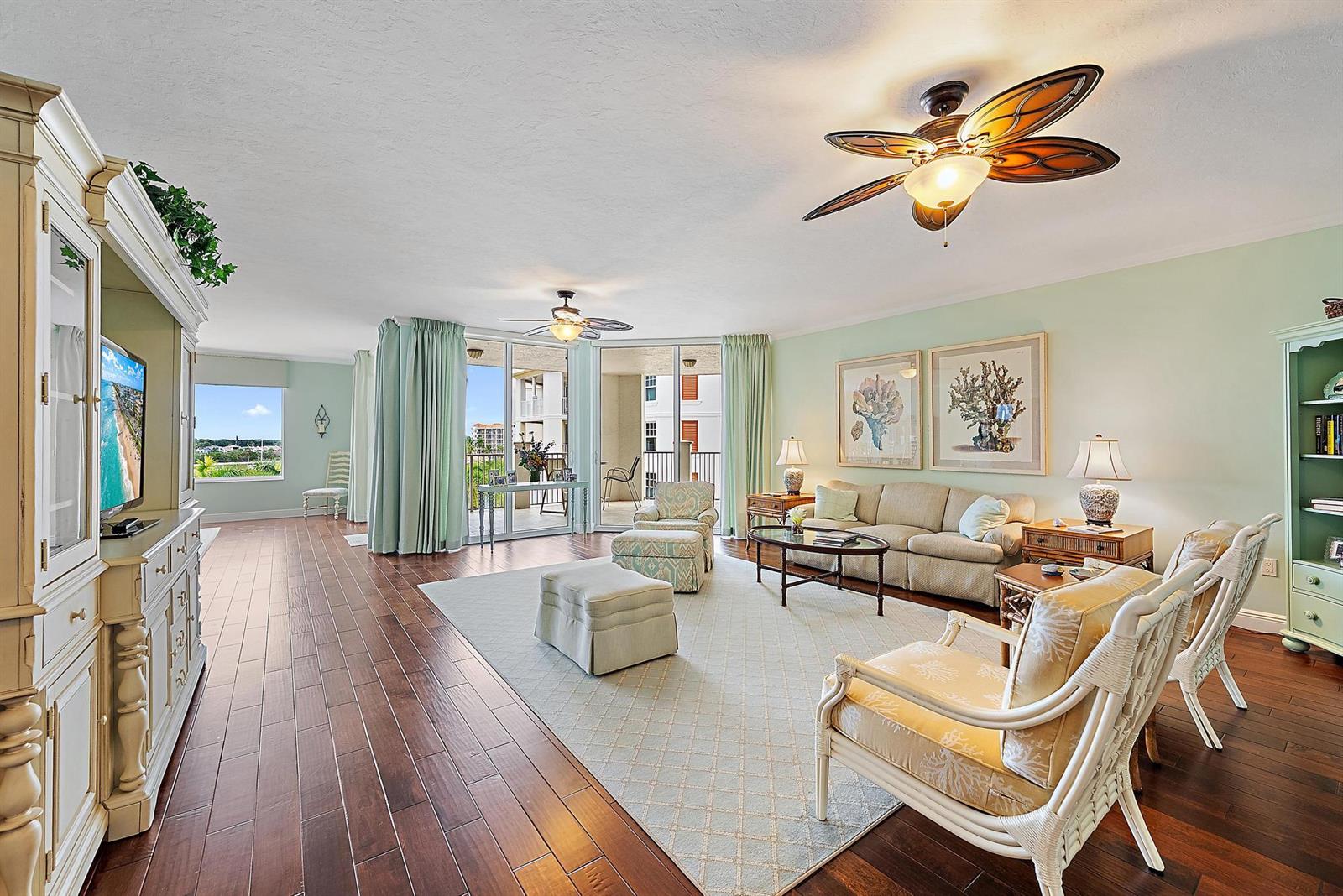 A living room features hardwood floors, a ceiling fan, a sofa, and a balcony view — 700 S Us Highway 1 # 406, Jupiter FL 33477, JUPITER, FL