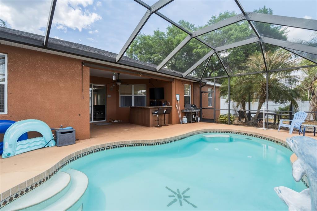 A screened-in patio features a swimming pool, an outdoor bar, and a grill area — 2486 LAWYER TERRACE, NORTH PORT, FL