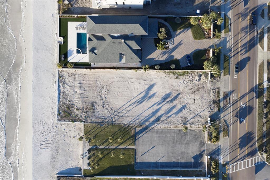An aerial view shows a vacant sandy lot situated between a house and a parking lot — 620.5 GULF BOULEVARD, BELLEAIR SHORE, FL