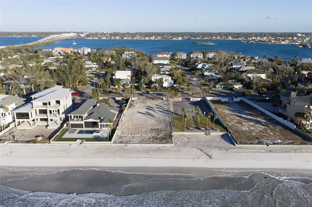 An aerial view shows two vacant beachfront lots situated between a house and a building — 620.5 GULF BOULEVARD, BELLEAIR SHORE, FL