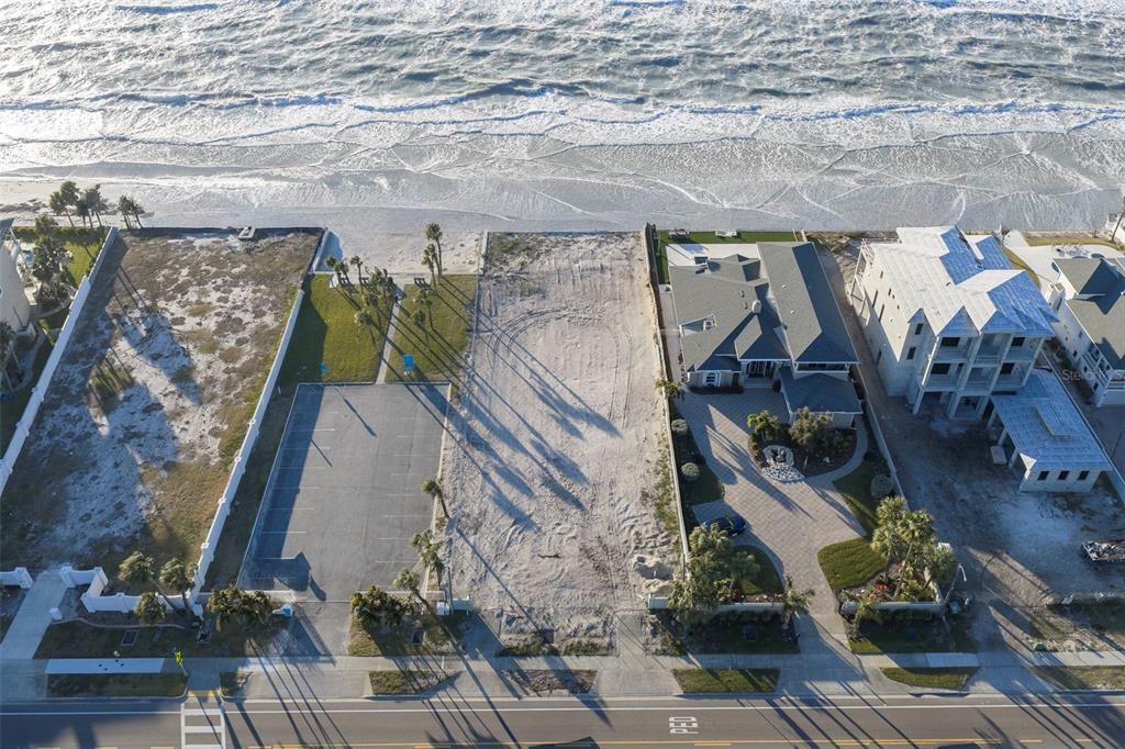 An aerial view shows a vacant beachside lot situated between two residential properties — 620.5 GULF BOULEVARD, BELLEAIR SHORE, FL