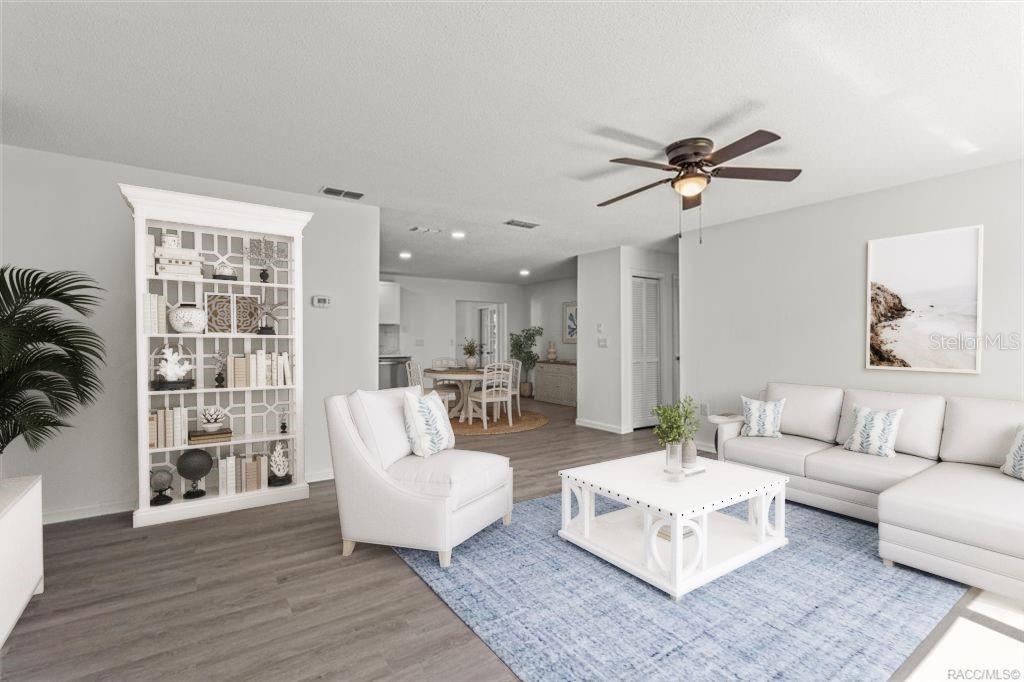 A living room features a white sectional sofa, armchair, coffee table, and a tall bookshelf — 5700 S CALGARY TERRACE, INVERNESS, FL