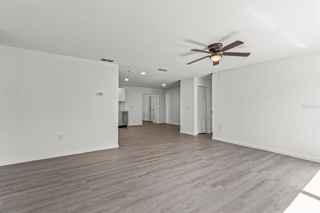 An open living area features light gray wood-look flooring, white walls, and a ceiling fan — 5700 S CALGARY TERRACE, INVERNESS, FL