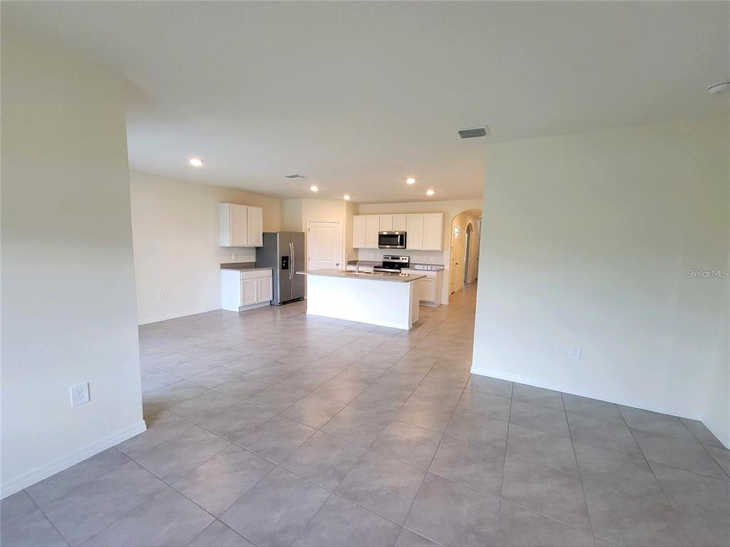 An open-concept kitchen features white cabinets, stainless steel appliances, and a central island — 17419 HARVEST MOON WAY, BRADENTON, FL