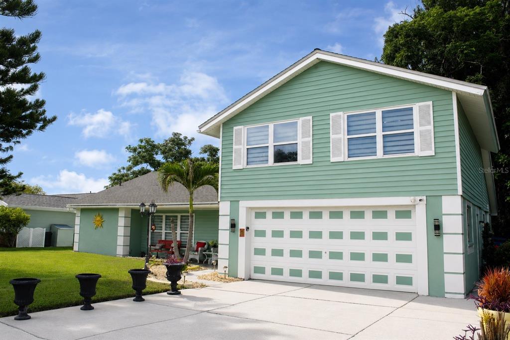 A two-story house with green siding, a white garage door, and a concrete driveway — 12416 COBBLE STONE DRIVE, HUDSON, FL