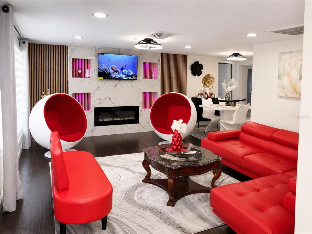 A living room features a marble fireplace wall, red furniture, and two white egg chairs — 12416 COBBLE STONE DRIVE, HUDSON, FL