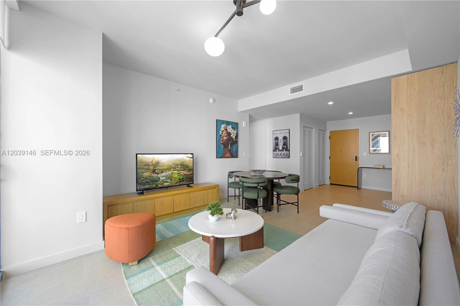 A living and dining area features a light gray sofa, round coffee table, and television — 11 NE 6th St # 1111, Miami FL 33132, MIAMI, FL