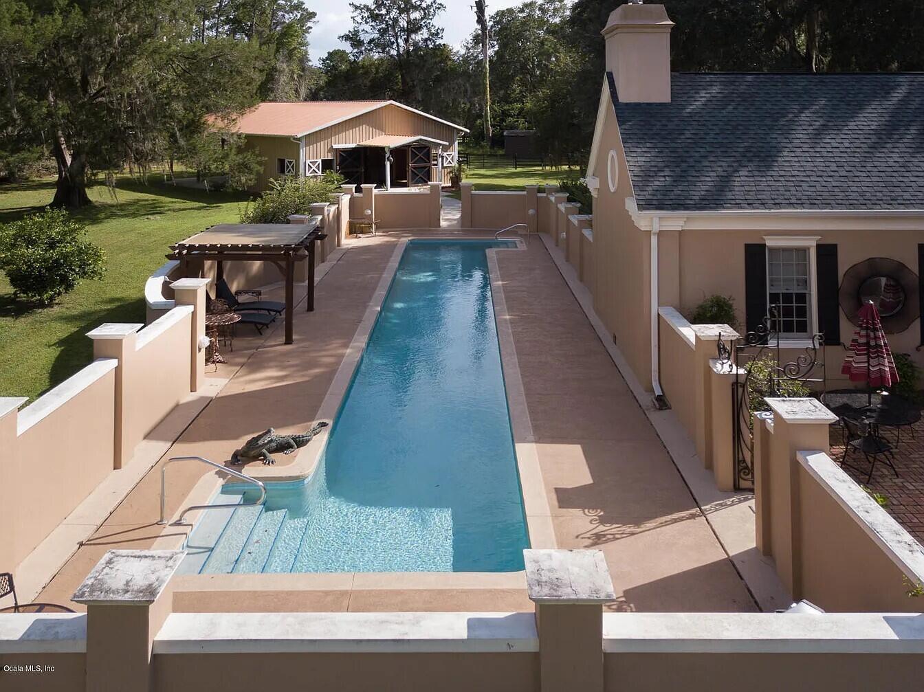 An aerial view shows a long, narrow lap pool enclosed by walls beside a house — 2030 SW 61st Lane Road, Ocala FL 34471, OCALA, FL