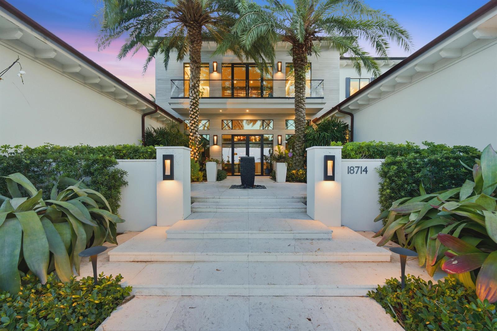 A modern two-story house features a stone entryway with palm trees and a water fountain — 18714 Rio Vista Drive, Jupiter FL 33469, JUPITER, FL