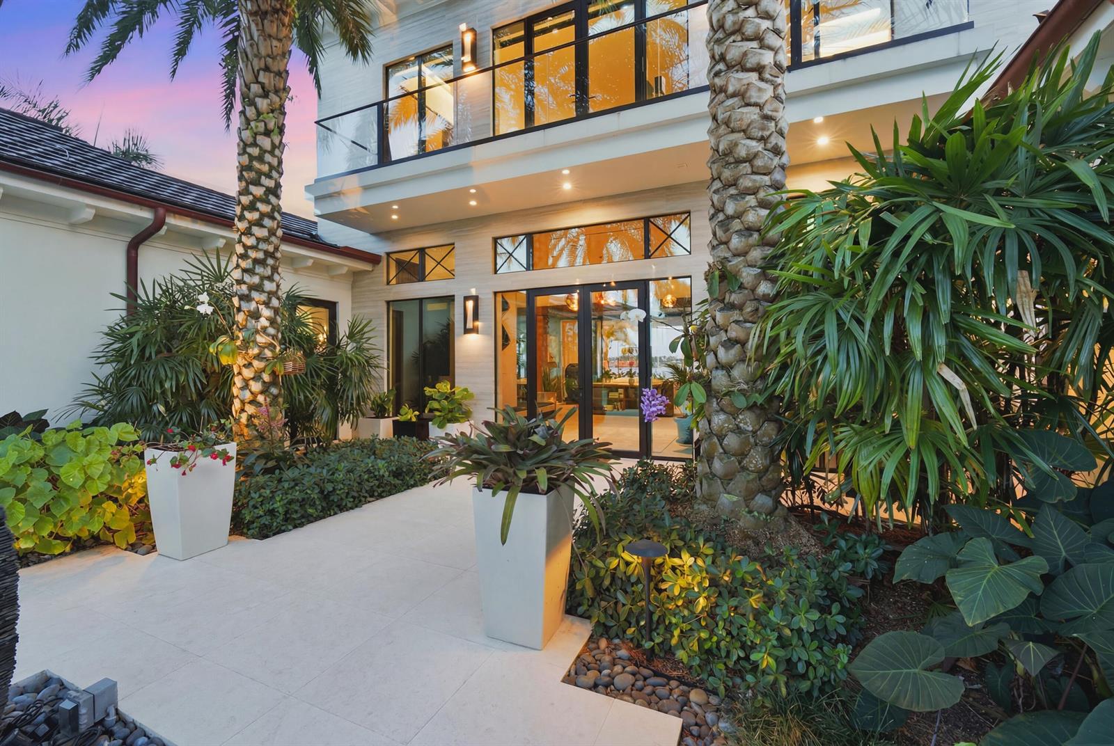 A paved walkway leads to the entrance of a modern two-story home with palm trees — 18714 Rio Vista Drive, Jupiter FL 33469, JUPITER, FL