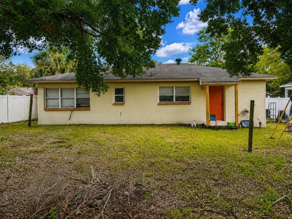 The exterior of a single-story, light-colored concrete block house with a bright orange front door — 712 N CASTLE COURT, TAMPA, FL