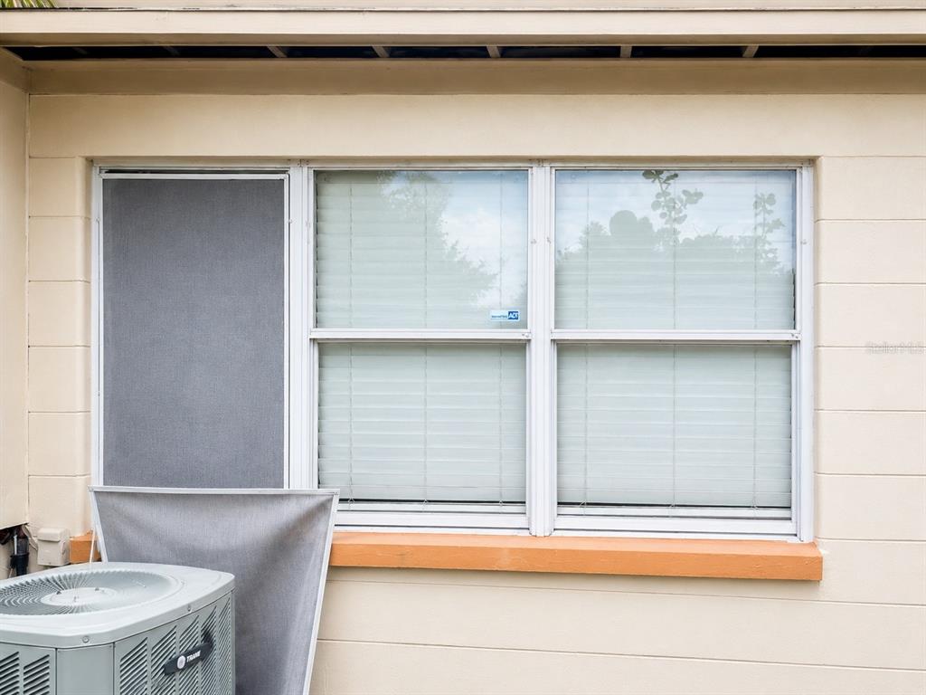 A beige exterior wall features a window with a screen and a nearby air conditioner — 712 N CASTLE COURT, TAMPA, FL